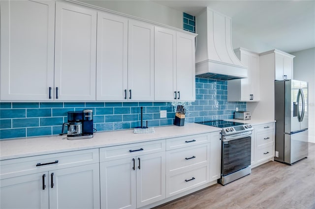 kitchen featuring appliances with stainless steel finishes, premium range hood, white cabinetry, and tasteful backsplash