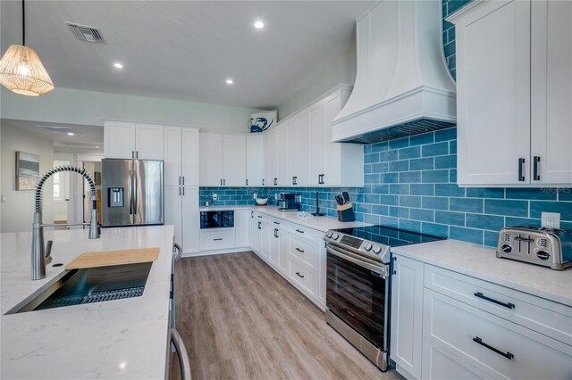 kitchen with premium range hood, white cabinetry, sink, and appliances with stainless steel finishes