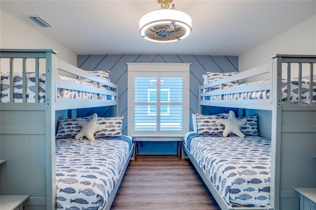 bedroom featuring hardwood / wood-style floors, ceiling fan, and wooden walls