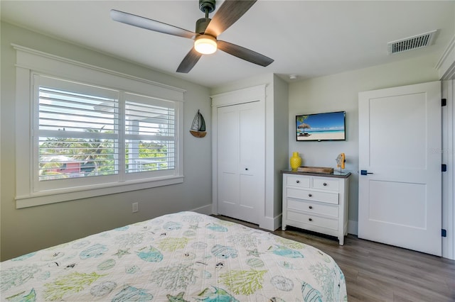 bedroom with ceiling fan, dark wood-type flooring, and a closet