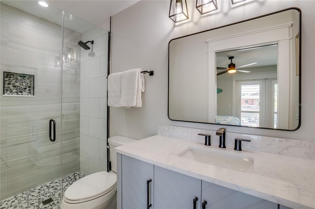 bathroom with vanity, toilet, ceiling fan, and a shower with shower door