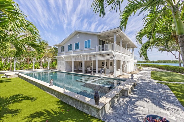 back of house with ceiling fan, a patio, a yard, a balcony, and a pool with hot tub