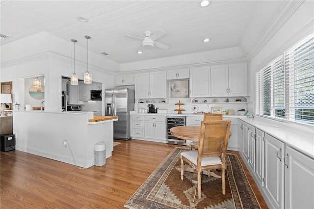 kitchen featuring light wood-style flooring, appliances with stainless steel finishes, white cabinets, a kitchen island, and beverage cooler