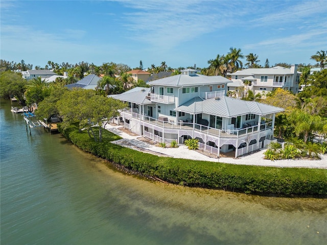 rear view of house with metal roof, a water view, a residential view, and a balcony