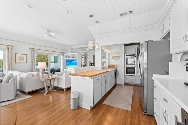 kitchen with open floor plan, butcher block countertops, white cabinetry, and pendant lighting