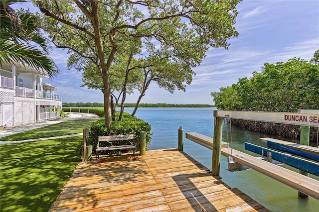 dock area with a balcony, a water view, and a lawn