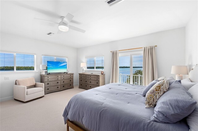 bedroom with a water view, access to outside, light colored carpet, and ceiling fan