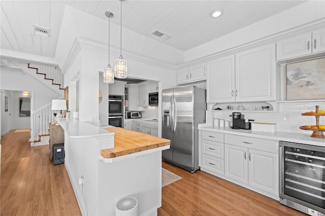 kitchen with wood counters, wine cooler, appliances with stainless steel finishes, and white cabinets