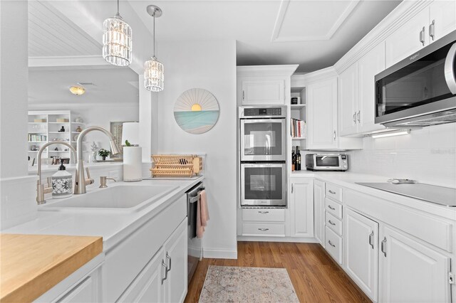 kitchen featuring light wood-type flooring, white cabinets, backsplash, stainless steel appliances, and sink