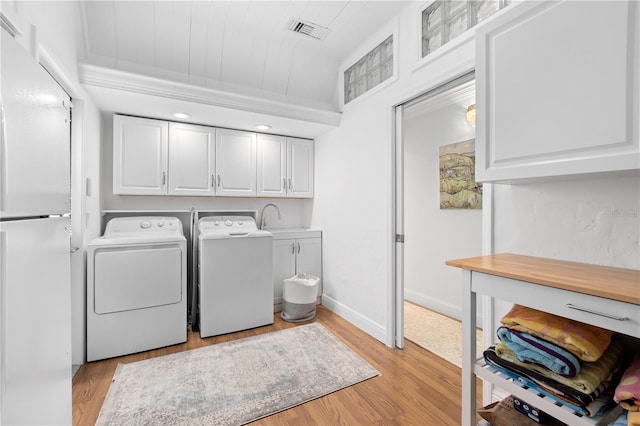 laundry room with visible vents, separate washer and dryer, light wood-style flooring, and cabinet space