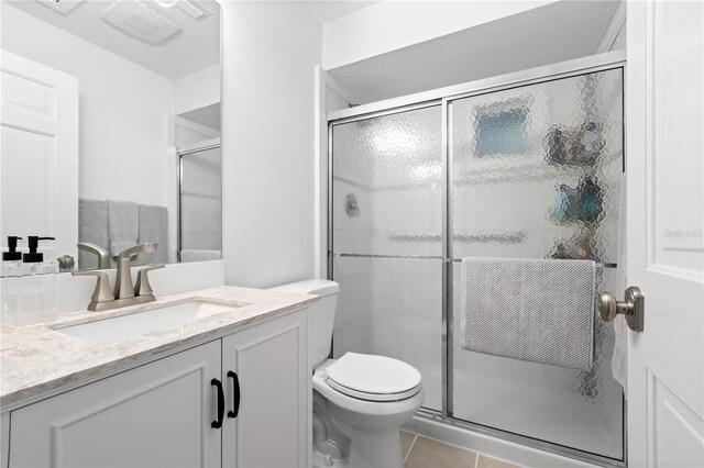 bathroom featuring vanity, walk in shower, toilet, and tile patterned floors