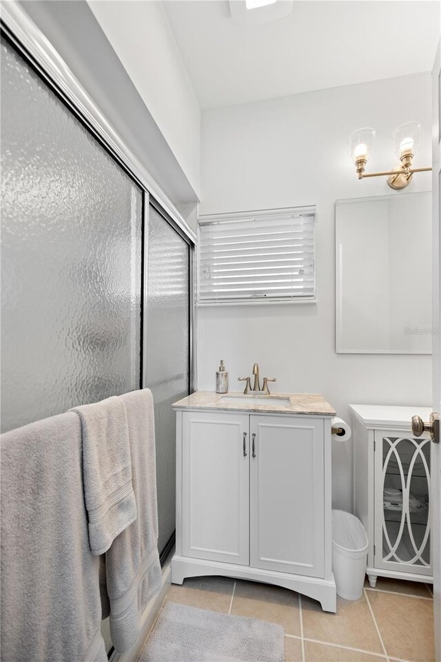 bathroom featuring tile patterned flooring, a shower with door, and vanity