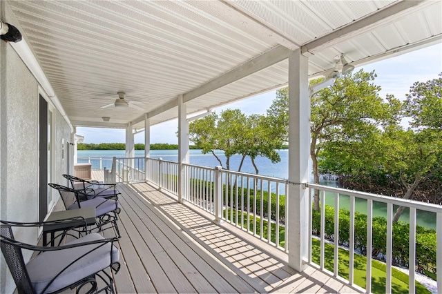 wooden deck featuring a water view, ceiling fan, and a lawn