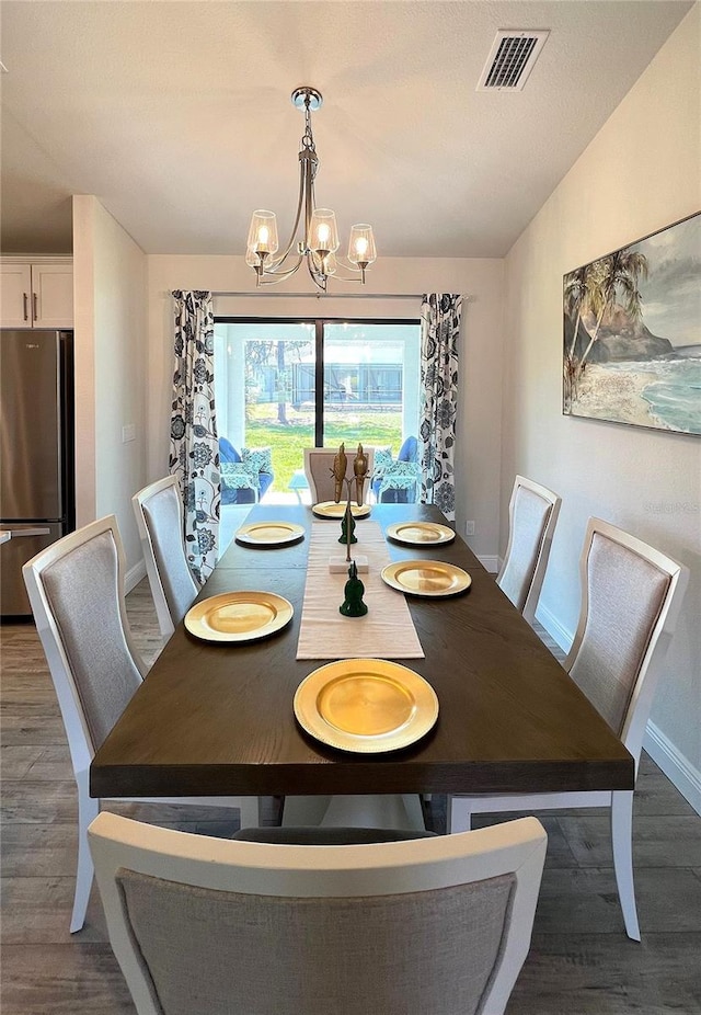 dining area with dark hardwood / wood-style floors and a notable chandelier