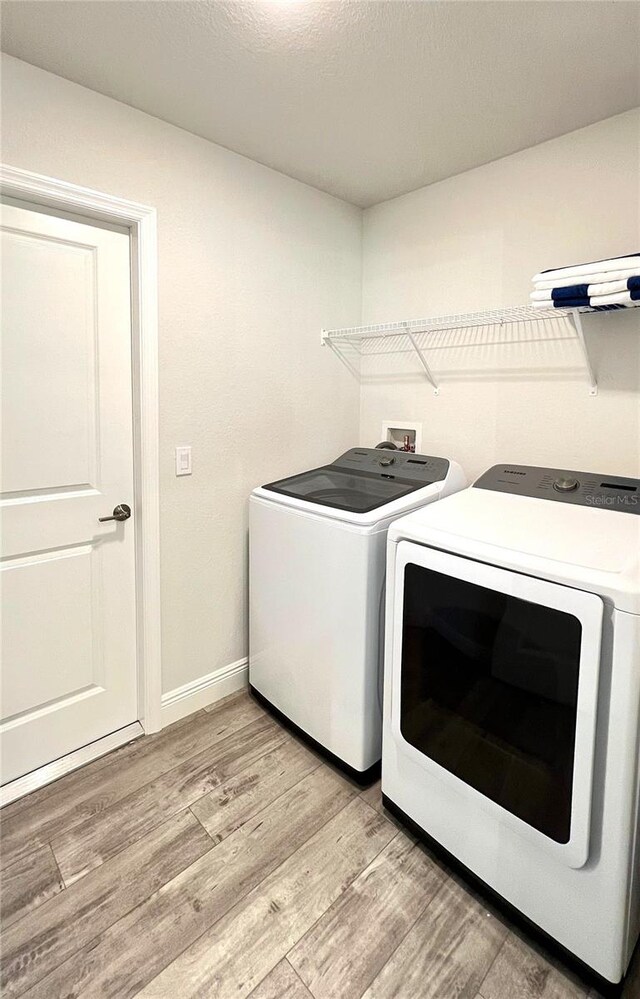 clothes washing area featuring washer and dryer and light hardwood / wood-style floors