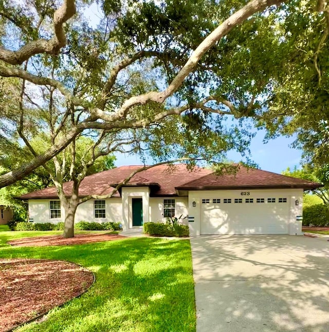 single story home featuring a garage and a front lawn