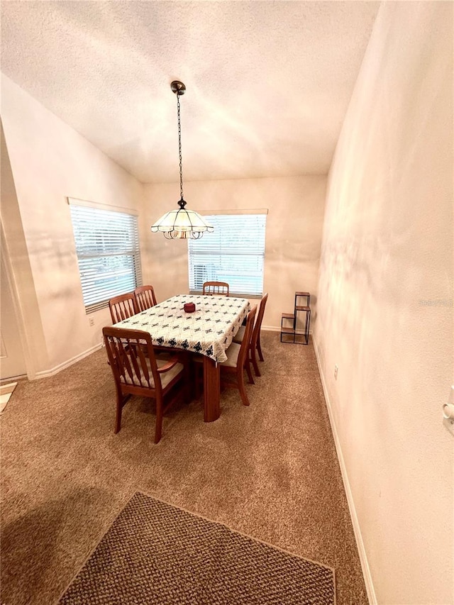 dining area with lofted ceiling, carpet flooring, and a textured ceiling