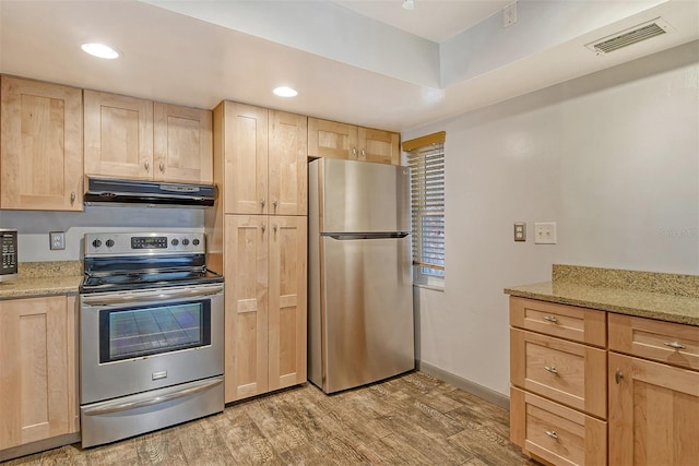 kitchen featuring light stone countertops, appliances with stainless steel finishes, light brown cabinets, and light wood-type flooring