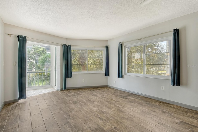 spare room with a wealth of natural light, a textured ceiling, and light wood-type flooring