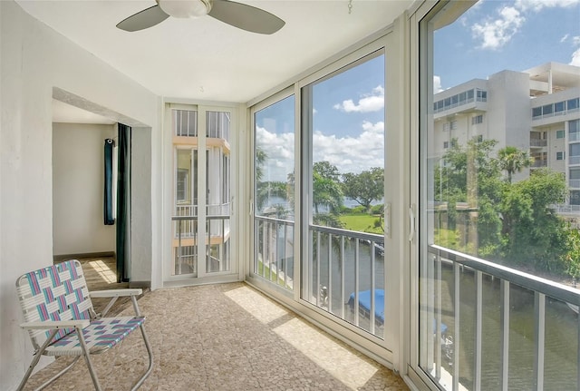 unfurnished sunroom with ceiling fan and a water view