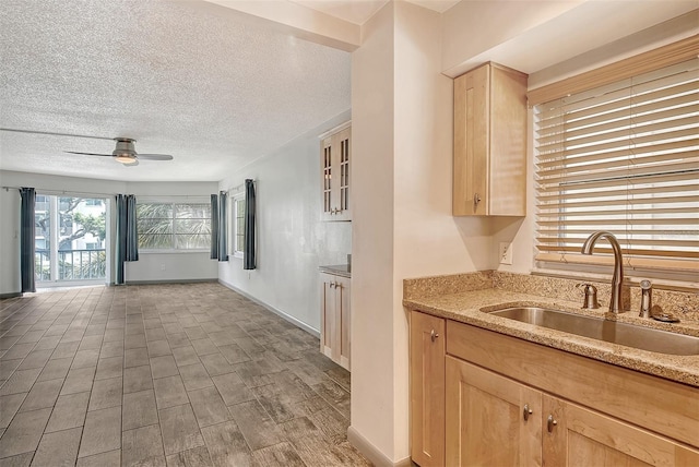 kitchen with ceiling fan, light stone countertops, sink, and light brown cabinetry