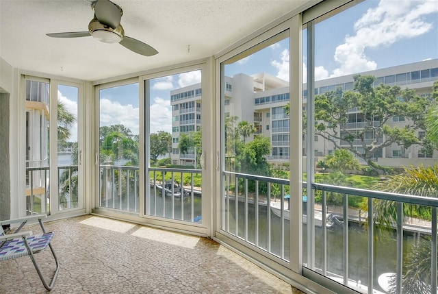 unfurnished sunroom with a water view and ceiling fan