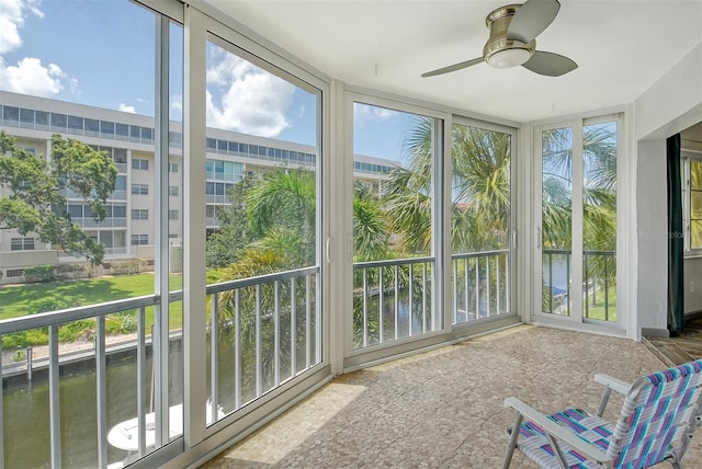 sunroom / solarium featuring a water view and ceiling fan