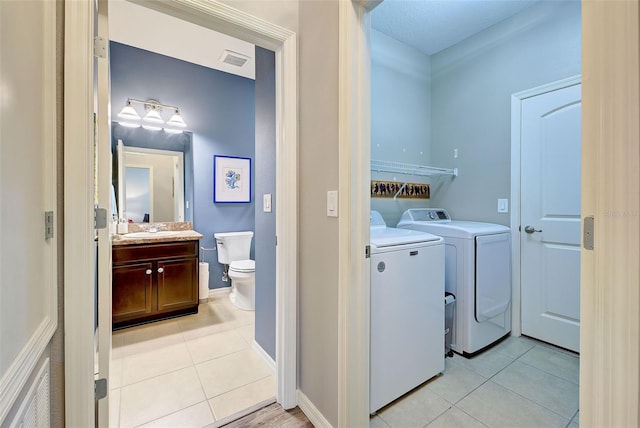 washroom featuring light tile patterned floors, washer and clothes dryer, and sink