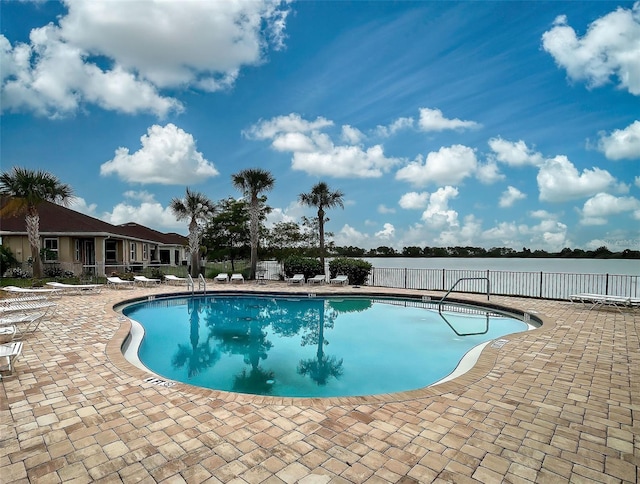 view of swimming pool featuring a water view and a patio