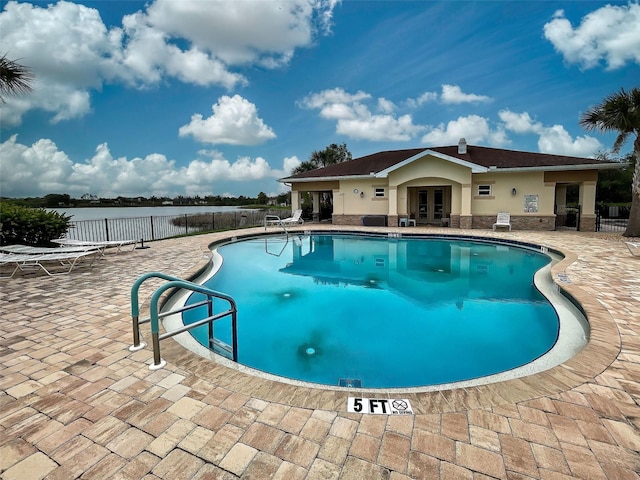 view of pool with french doors, a water view, and a patio area