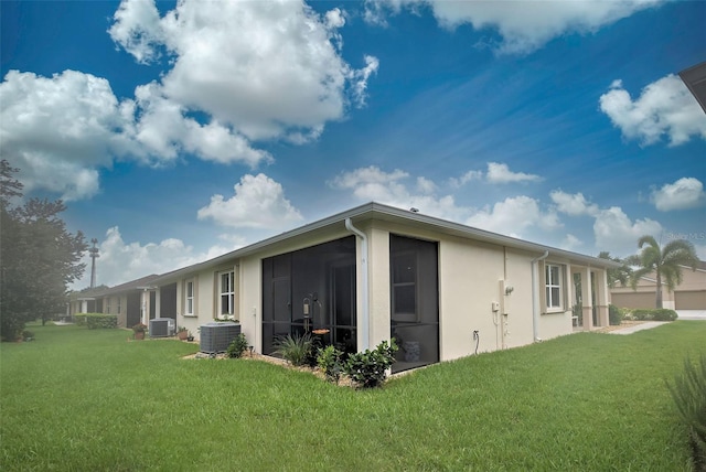 view of property exterior featuring a lawn, a sunroom, and central air condition unit