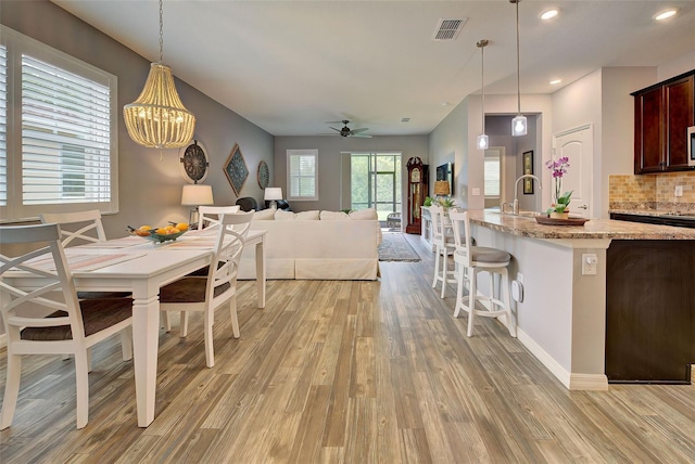 dining space with sink, ceiling fan, and light wood-type flooring