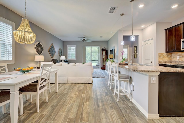 interior space with sink, ceiling fan with notable chandelier, and light hardwood / wood-style floors