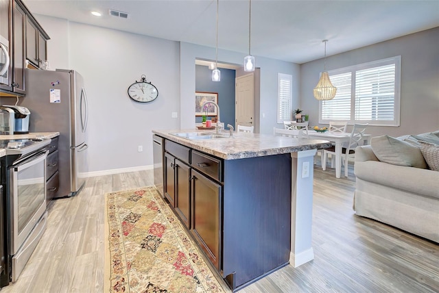 8930 Tuscany Isles Dr, Punta Gorda, FL 33950 - kitchen with appliances with stainless steel finishes, open floor plan, light wood-style flooring, dark brown cabinetry, and recessed lighting
