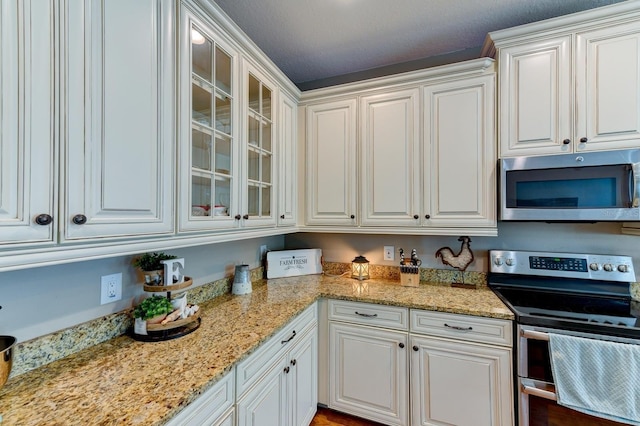 kitchen with appliances with stainless steel finishes, white cabinetry, and light stone countertops