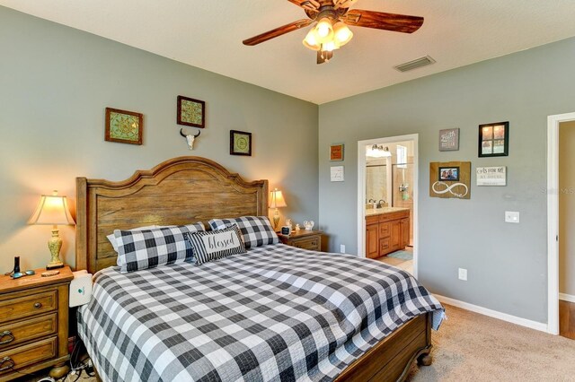 bedroom with ensuite bathroom, sink, light carpet, and ceiling fan