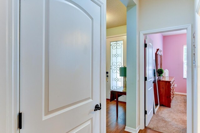 corridor featuring a textured ceiling, hardwood / wood-style flooring, and plenty of natural light