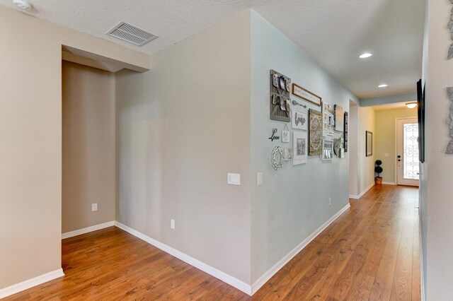 hall with hardwood / wood-style flooring and a textured ceiling