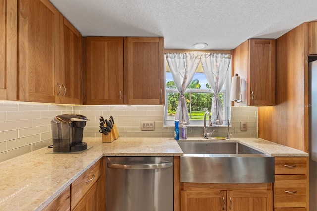 kitchen featuring sink, light stone counters, a textured ceiling, stainless steel dishwasher, and backsplash