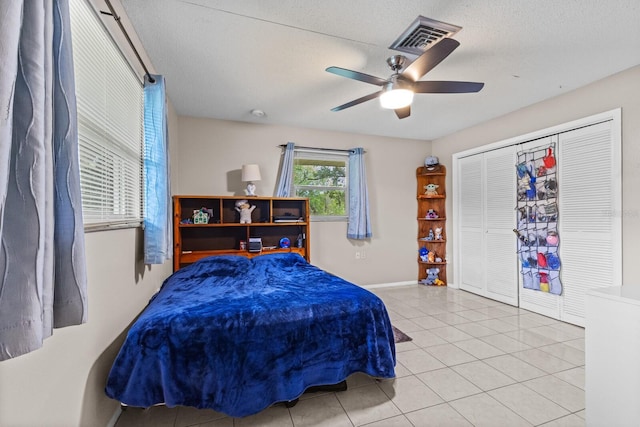 tiled bedroom with ceiling fan, a closet, and a textured ceiling