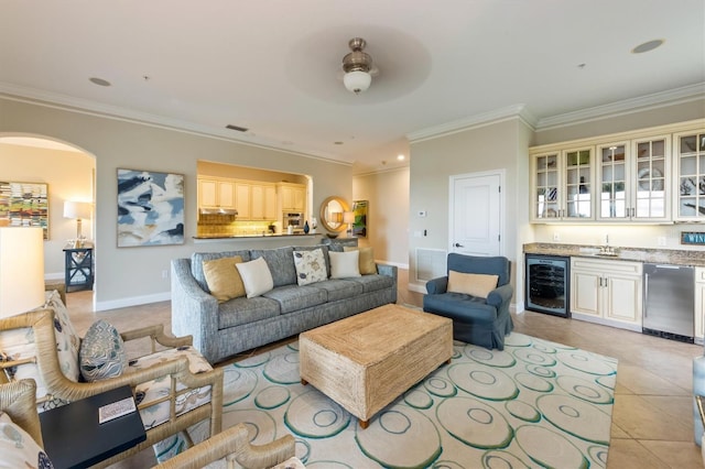 tiled living room featuring ceiling fan, beverage cooler, ornamental molding, and wet bar