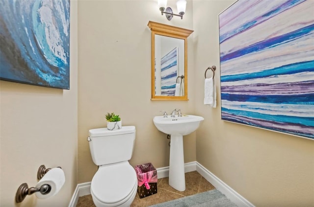 bathroom with toilet, sink, tile patterned floors, and an inviting chandelier