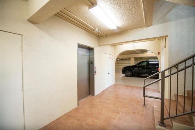 hallway featuring a textured ceiling and elevator