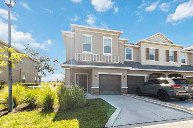 view of front of property with stucco siding, driveway, stone siding, roof with shingles, and an attached garage