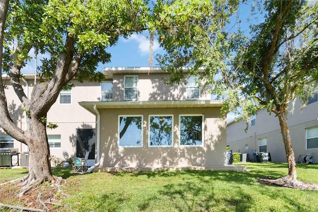 back of property featuring stucco siding, a lawn, and central AC