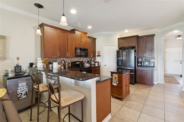 kitchen featuring a kitchen island, a peninsula, arched walkways, black appliances, and backsplash