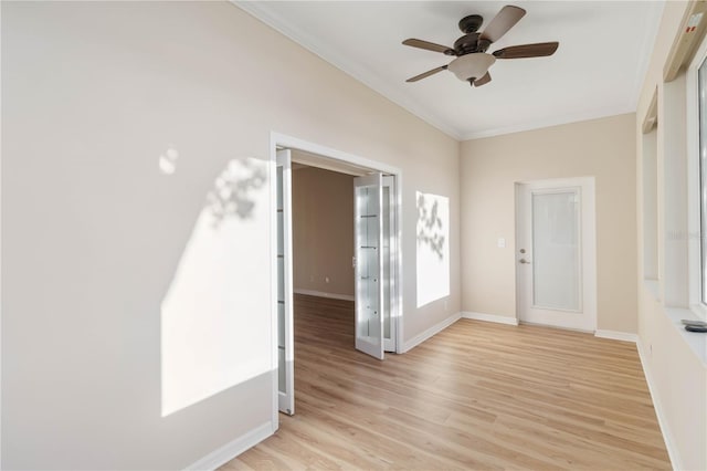 unfurnished room featuring crown molding, baseboards, light wood finished floors, and ceiling fan