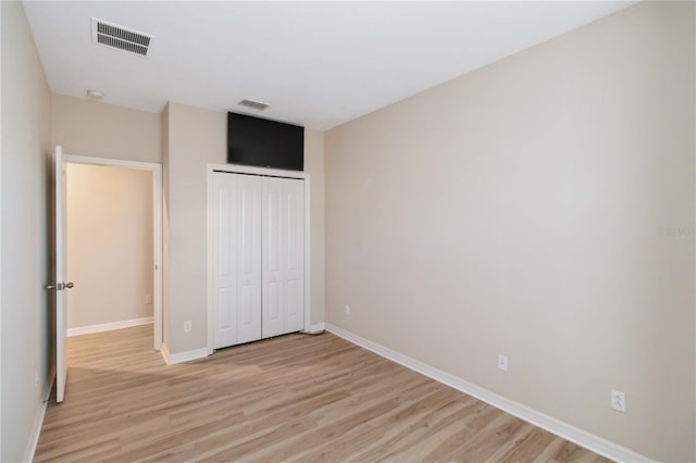 unfurnished bedroom featuring a closet, visible vents, light wood-style flooring, and baseboards