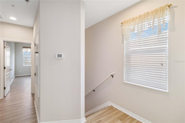 corridor with light wood-style flooring, recessed lighting, an upstairs landing, and baseboards