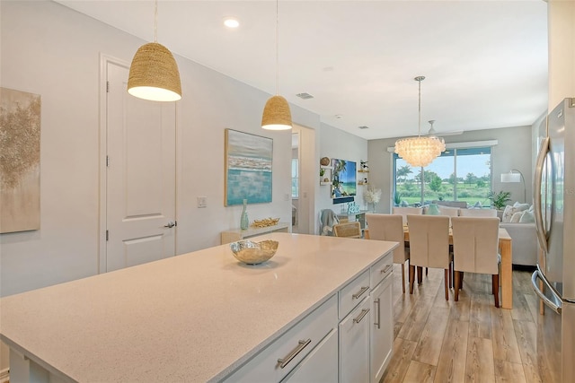 kitchen featuring stainless steel fridge, decorative light fixtures, light hardwood / wood-style floors, and white cabinets